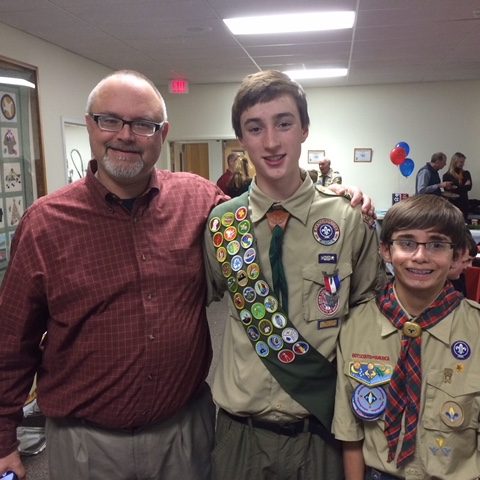 Father and two boys smiling at scout event